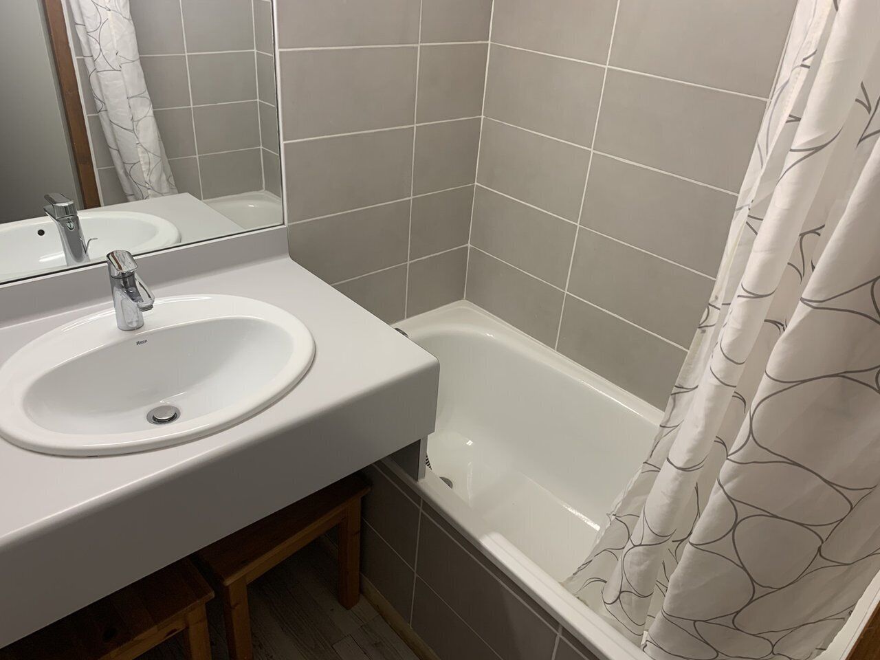 A bathroom with a white sink, mirror, and bathtub.