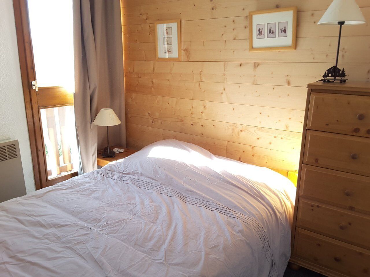 Una camera da letto con testiera in legno, un letto con biancheria bianca, un comodino con una lampada e un comò.