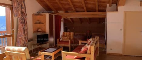 Un soggiorno con pavimento in legno, televisione, angolo salotto e vista sull'esterno.