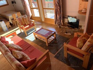 A cozy living room with a sofa, chairs, a coffee table, and a television.
