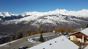 A mountain view with snow-covered peaks, a parking area, and a building with a sloped roof. - Paridiski closed to the slopes vallandry (LANDRY)