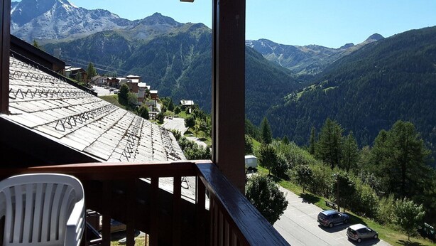 A balcony with a view of a mountain range, a parking area, and a white chair. - Paridiski closed to the slopes vallandry (LANDRY)