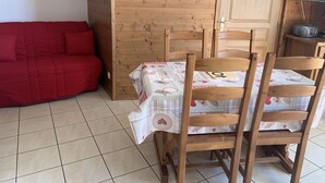 A wooden dining table with a checkered tablecloth, surrounded by wooden chairs. A red sofa is positioned against the wall. - Paradiski closed to the slopes plan peisey (PEISEY-NANCROIX)