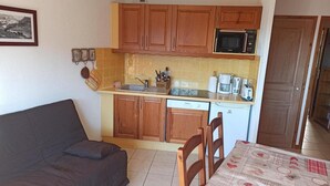 A compact kitchen with wooden cabinets, a microwave, and a dishwasher. A dining table with a patterned tablecloth is in the foreground. - Paradiski closed to the slopes plan peisey (PEISEY-NANCROIX)