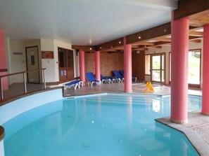 An indoor swimming pool with blue water, surrounded by pink columns, and blue lounge chairs. - Paradiski closed to the slopes plan peisey (PEISEY-NANCROIX)