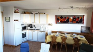 Una cocina compacta con armarios blancos, una mesa de comedor con platos y una obra de arte en la pared con sombreros.