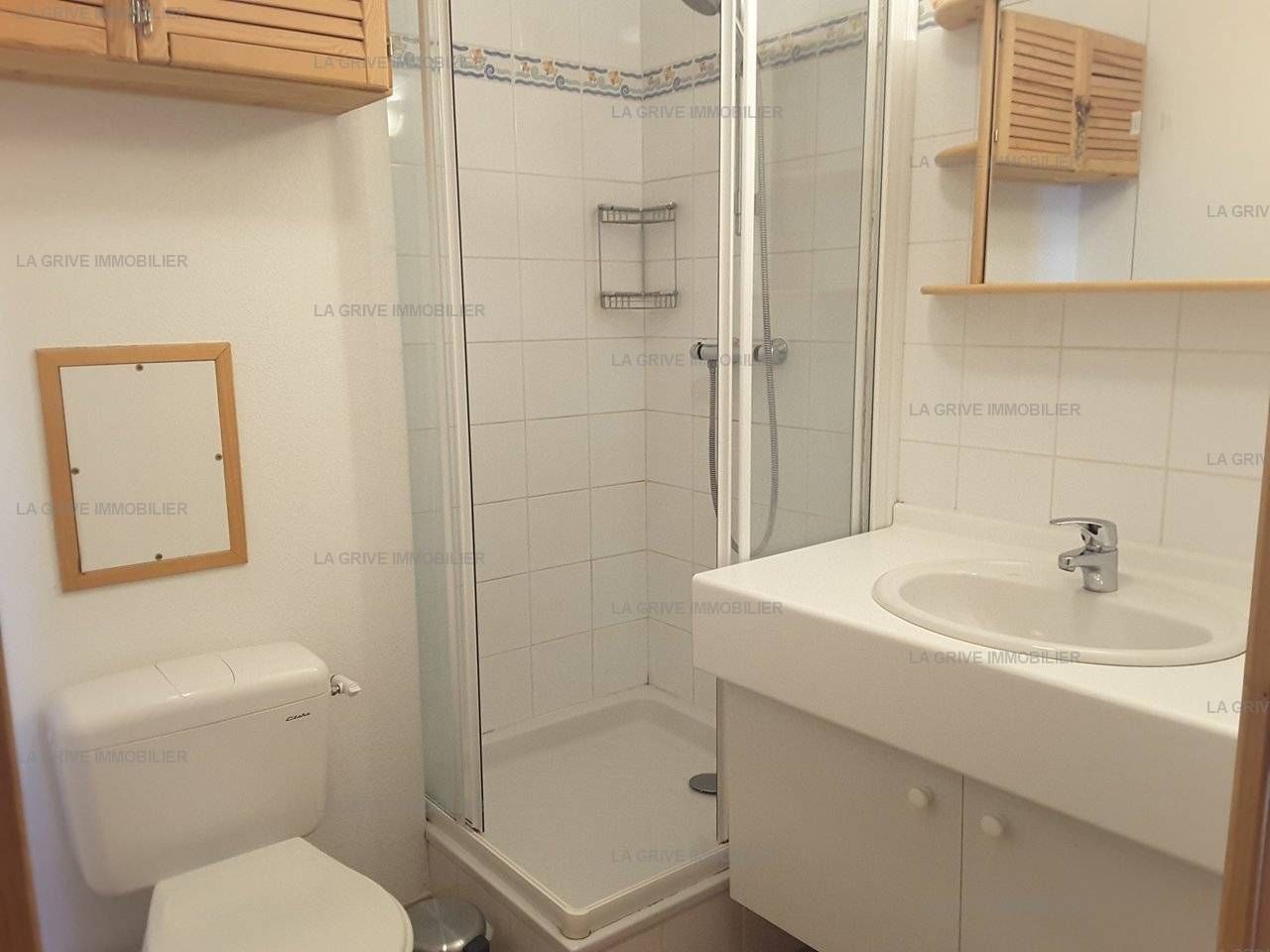 A bathroom with a glass-enclosed shower, a white sink, and a toilet.