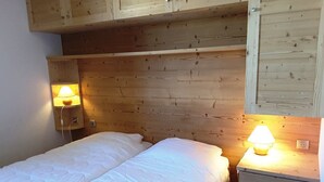 Una habitación pequeña y acogedora con cabecera de madera, dos mesitas de noche con lámparas y una cama con ropa blanca.