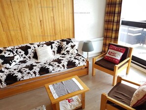 Un salon comprenant un canapé, deux fauteuils, une table basse et une lampe.