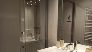 A modern bathroom with a glass-enclosed shower, a white sink with a mirror, and a towel rack. - Paradiski renovated apartment vallandry (LANDRY)