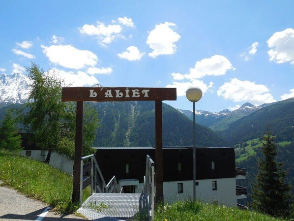 Ein Holzschild mit dem Schriftzug "LALIET" über einer Treppe, die zu einem Gebäude führt.