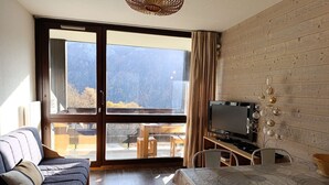 A modern living room with a sofa, a dining table, and a TV.