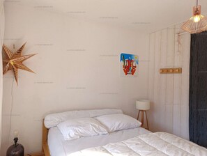 Un dormitori amb un llit, una decoració d'estels, una obra d'art a la paret, una làmpada i una cortina.