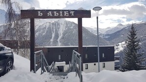 A snow-covered entrance with a sign reading "BALIET" and a building in the background.