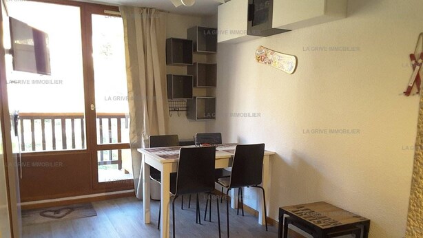 A dining area with a table and chairs, a small table with a decorative item, and a sliding door leading to an outdoor area.