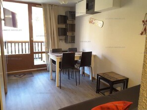 A dining area with a table and chairs, a small table with a decorative item, and a sliding door leading to an outdoor area. - Paradiski ski in ski out in vallandry (LANDRY)