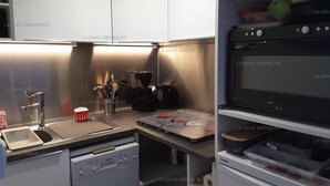 A modern kitchen with a dishwasher, coffee maker, and a flat-screen TV.