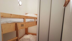 Een stapelbed met een houten frame en witte beddengoed.