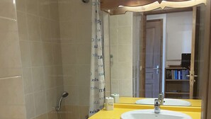 Une salle de bain avec une baignoire, deux lavabos, un miroir et un rideau de douche.