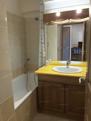 Une salle de bain avec une baignoire, deux lavabos, un miroir et un rideau de douche.