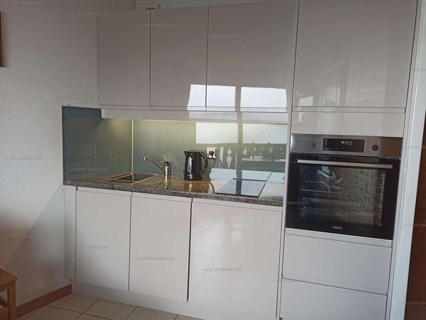 A modern kitchen with white cabinets, a stainless steel oven, and a built-in dishwasher.