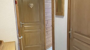 A hallway with a wooden door, a small mirror on the wall, and a tiled floor. - Apartment closed to the slopes in plan peisey (PEISEY-NANCROIX)
