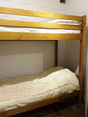 A bunk bed with a wooden frame and white bedding.