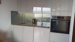 A modern kitchen with white cabinets, a stainless steel sink, a kettle, and an oven. - Apartment closed to the slopes in plan peisey (PEISEY-NANCROIX)