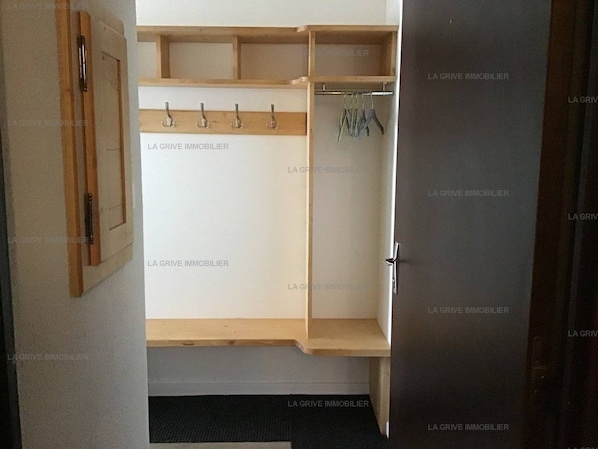 Une pièce avec une armoire en bois, un porte-manteau et une porte.