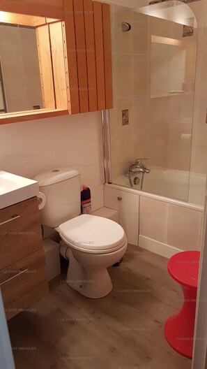 Une salle de bain avec des toilettes, une douche et un abattant de toilettes rouge.