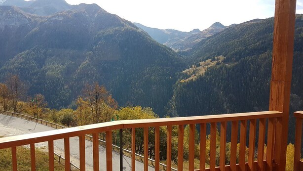 Une vue sur la montagne depuis un balcon doté d’une balustrade en bois.