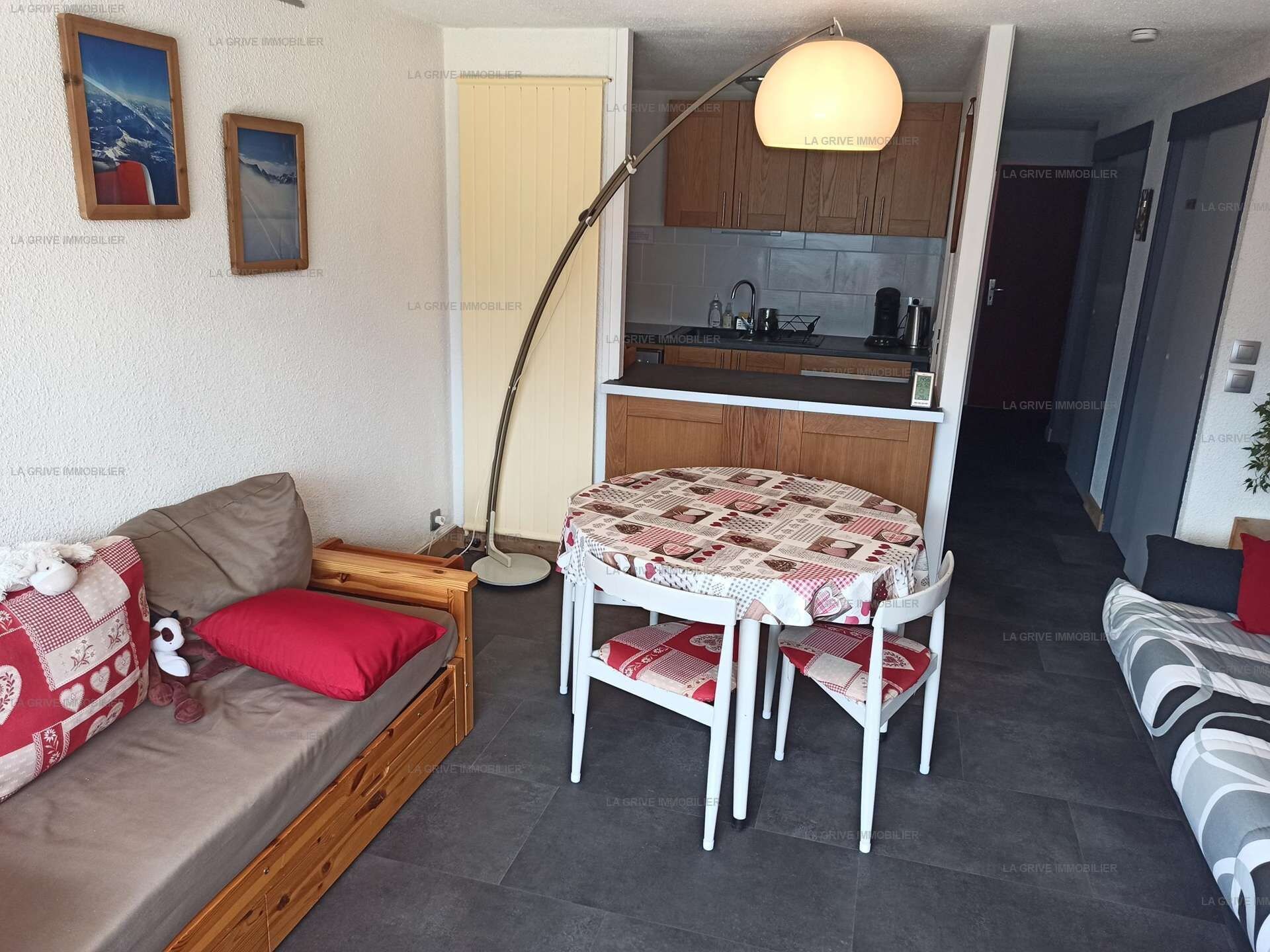A compact living space with a sofa, a small dining table, and a kitchenette in the background.