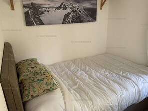 A bedroom with a bed, pillows, a headboard, and a framed picture on the wall.