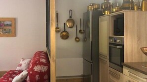 Un espace de vie compact comprenant un coin cuisine, un canapé agrémenté de coussins à motifs et un porte-ustensiles fixé au mur.