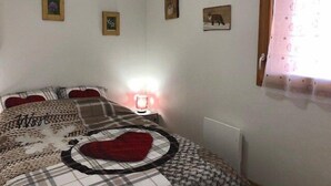 Une chambre à coucher avec un lit, une lampe de chevet et trois tableaux encadrés accrochés au mur.