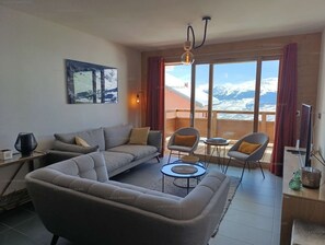 A living room with a sofa, chairs, a coffee table, and a painting on the wall.