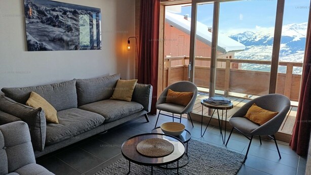 A modern living room with a sofa, armchairs, a coffee table, and a painting.