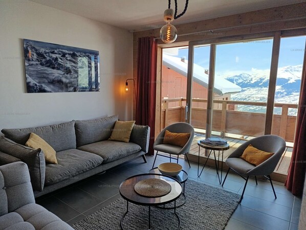 A modern living room with a sofa, armchairs, a coffee table, and a painting.