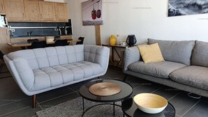 A modern living room with a grey sofa, a matching armchair, and a coffee table with a woven placemat.