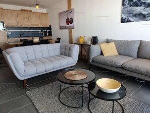 A modern living room with a grey sofa, a matching armchair, and a coffee table with a woven placemat.