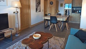 Ett modernt vardagsrum med en TV, ett matbord och ett köksområde med skåp och en mikrovågsugn.