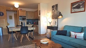 Ett mysigt vardagsrum med en blå soffa, ett matbord i trä med stolar och ett soffbord med en skål på.