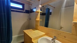 Een badkamer met een houten wastafelmeubel, een wastafel, een spiegel en een douchehoek.