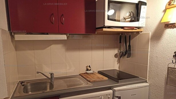 A compact kitchen with a microwave, sink, and a dishwasher.