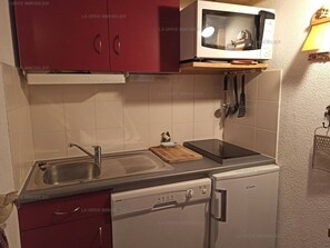 Eine kleine Küche mit Mikrowelle, Spüle und Geschirrspüler.