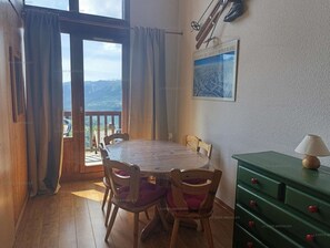 Uma sala de jantar com uma mesa e cadeiras de madeira, um armário verde e um quadro na parede.