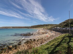 A coastal beach with rocky shores, a clear sky, and a hilly landscape in the background. - Starfish (Penzance)