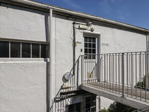 A white building with a metal balcony, a door labeled "Sonnen Heights," and a window with blinds. - Starfish (Penzance)