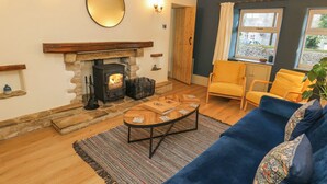 Ein gemütliches Wohnzimmer mit Kamin aus Stein, einem blauen Sofa und einem gelben Sessel.