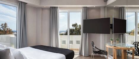 A modern hotel room with a large bed, a TV, a glass table, and a balcony with a view.